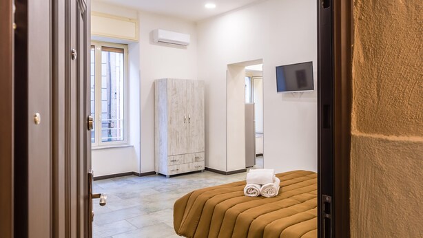 Une chambre d’hôtel équipée d’un lit, d’une armoire, d’un climatiseur, d’une télévision et d’une fenêtre.