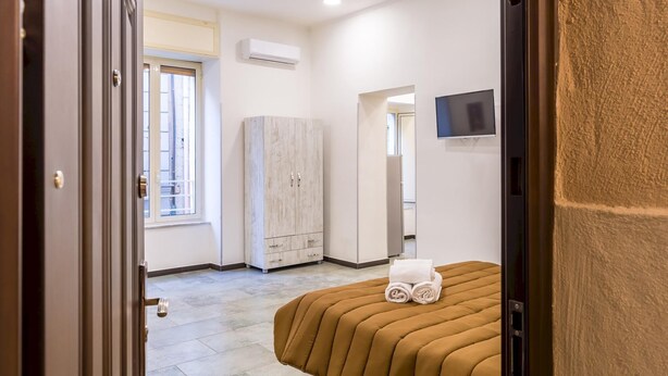A bedroom with a bed, a wardrobe, a TV, and an air conditioning unit. - Studios 1 in Napoli With 1 Bathrooms (Naples)
