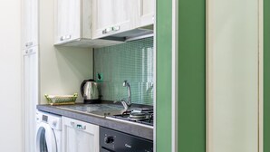 A compact kitchen with a washing machine, oven, and a green tiled backsplash. - Studios 1 in Napoli With 1 Bathrooms (Naples)