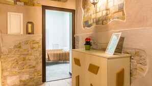 A hotel lobby with stone walls, a white reception desk, and a view into a room with a bed and a chair. - Studios 1 in Napoli With 1 Bathrooms (Naples)