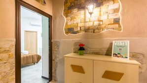A hotel reception area with a stone wall, a signboard, a potted plant, and a bed in the background. - Studios 1 in Napoli With 1 Bathrooms (Naples)