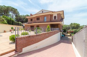 A two-story house with a brick facade, a balcony, and a paved driveway.