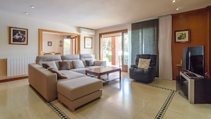 A modern living room with a sectional sofa, a coffee table, a leather armchair, and a television. - Club Villamar - Superbly presented family villa located in one of the most beautiful neighbourhoo... (Lloret de Mar)