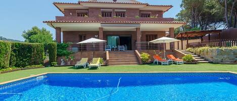A two-story house with a swimming pool in the foreground.