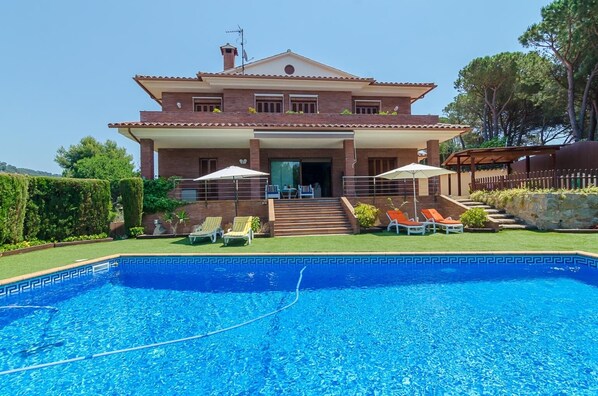 A two-story house with a swimming pool in the foreground.