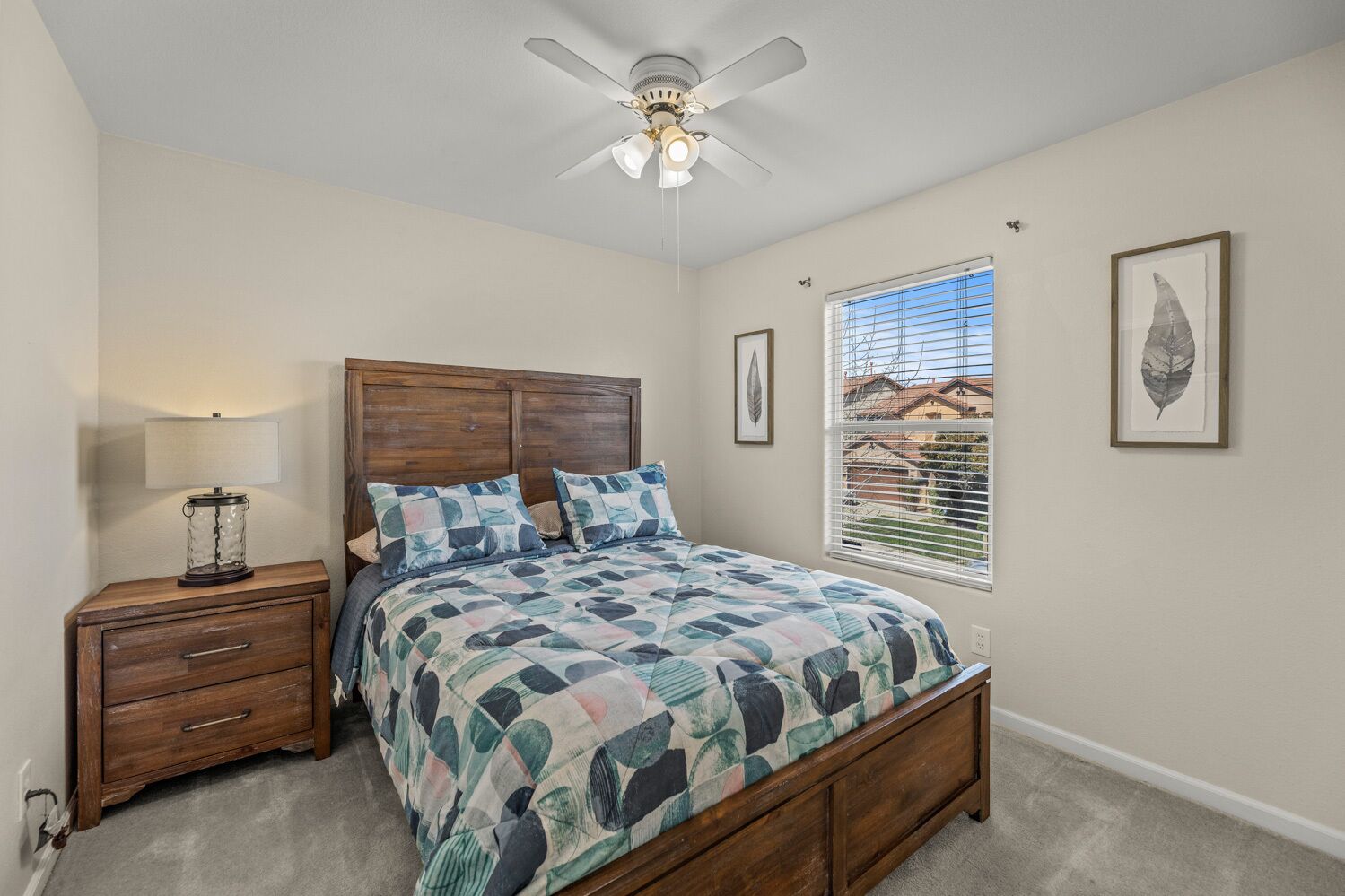 A bedroom with a wooden bed, a nightstand, a ceiling fan, and a window with blinds.