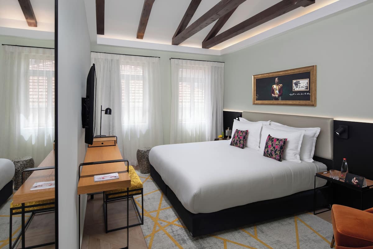 Une chambre d’hôtel moderne, dotée d’un grand lit, d’un bureau et d’une télévision.