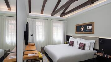 Une chambre d’hôtel moderne, dotée d’un grand lit, d’un bureau et d’une télévision.