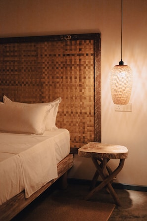 A bedroom with a wooden headboard, a bedside table, and a hanging light fixture. - Manta Reserve (Maalhos)