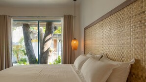 A bedroom with a large bed, a woven headboard, and a view of palm trees through a sliding door. - Manta Reserve (Maalhos)