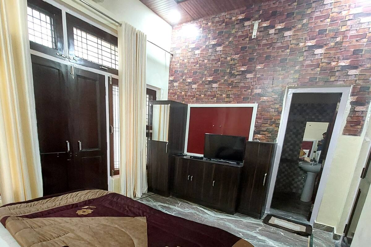 Una habitación con cama, televisión, escritorio y baño.
