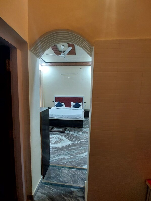 Un estrecho pasillo que conduce a un dormitorio con cama, ventilador de techo y piso estampado.
