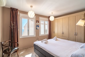 A bedroom with a bed, a bench, a wardrobe, and a window with curtains. - Villa Seaview Punta Lara by Casasol (Nerja)