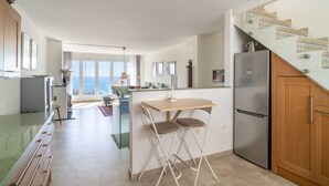 A modern kitchen with a dining area, a refrigerator, and a view of the city. - Villa Seaview Punta Lara by Casasol (Nerja)