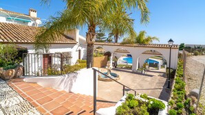 A courtyard with a pool, palm trees, and a tiled patio. - Villa Seaview Punta Lara by Casasol (Nerja)
