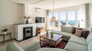 A living room with a sofa, a coffee table, a fireplace, a TV, and a view of the sea. - Villa Seaview Punta Lara by Casasol (Nerja)