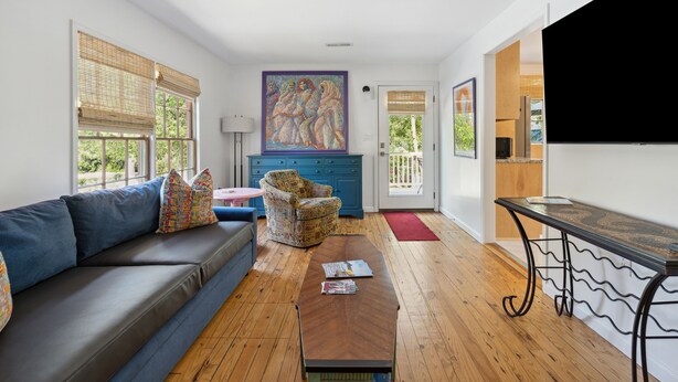 Un salon moderne avec un canapé, un fauteuil à motifs, une table basse et un tableau accroché au mur.