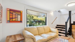 Un salon moderne avec un canapé en cuir beige, une table basse en bois et un tableau accroché au mur.