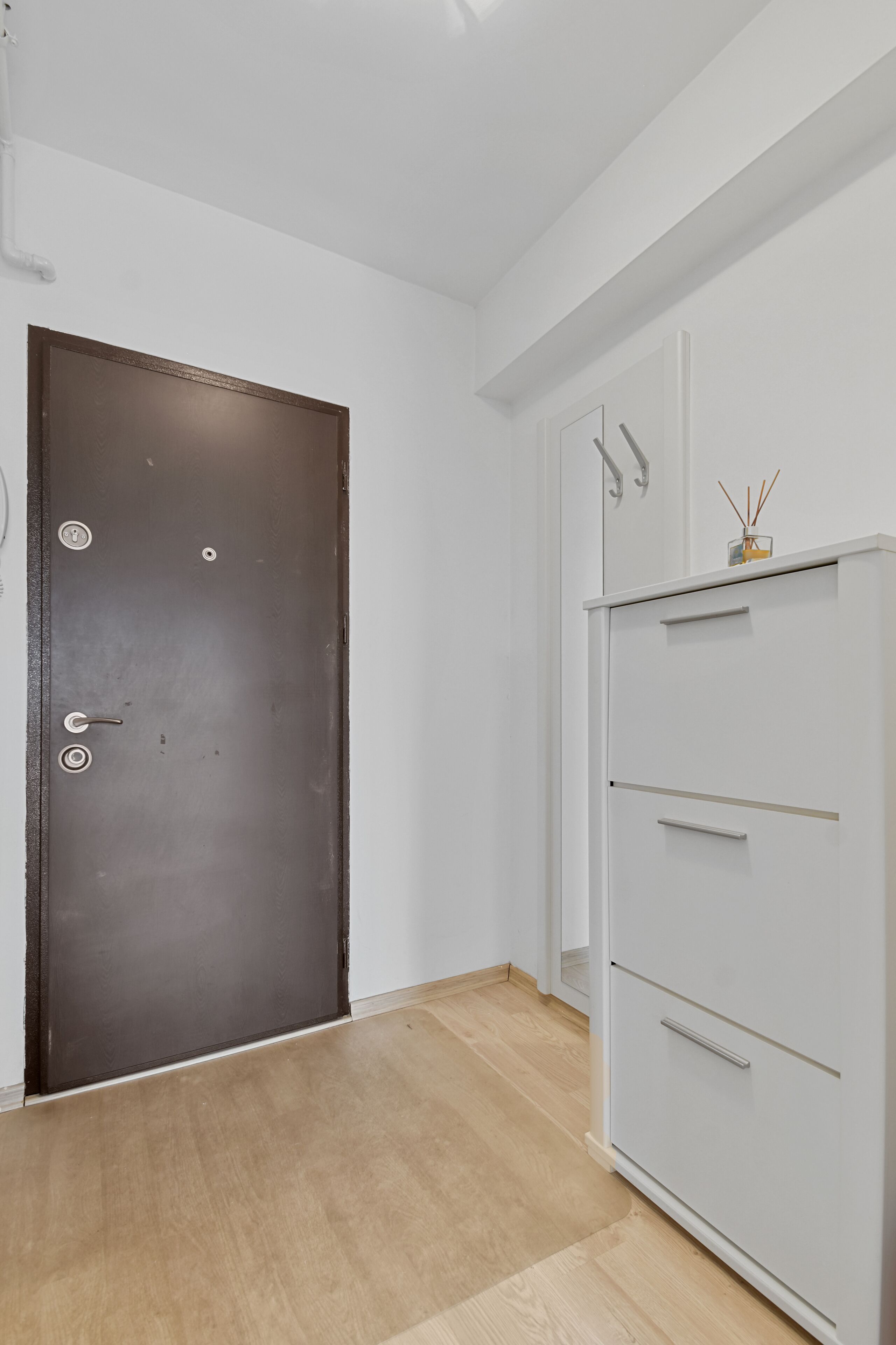 A room with a wooden door, a white wardrobe, and a small decorative item on top.