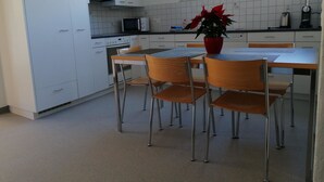 Ett kök med vita skåp, en mikrovågsugn, en klocka och ett fönster.