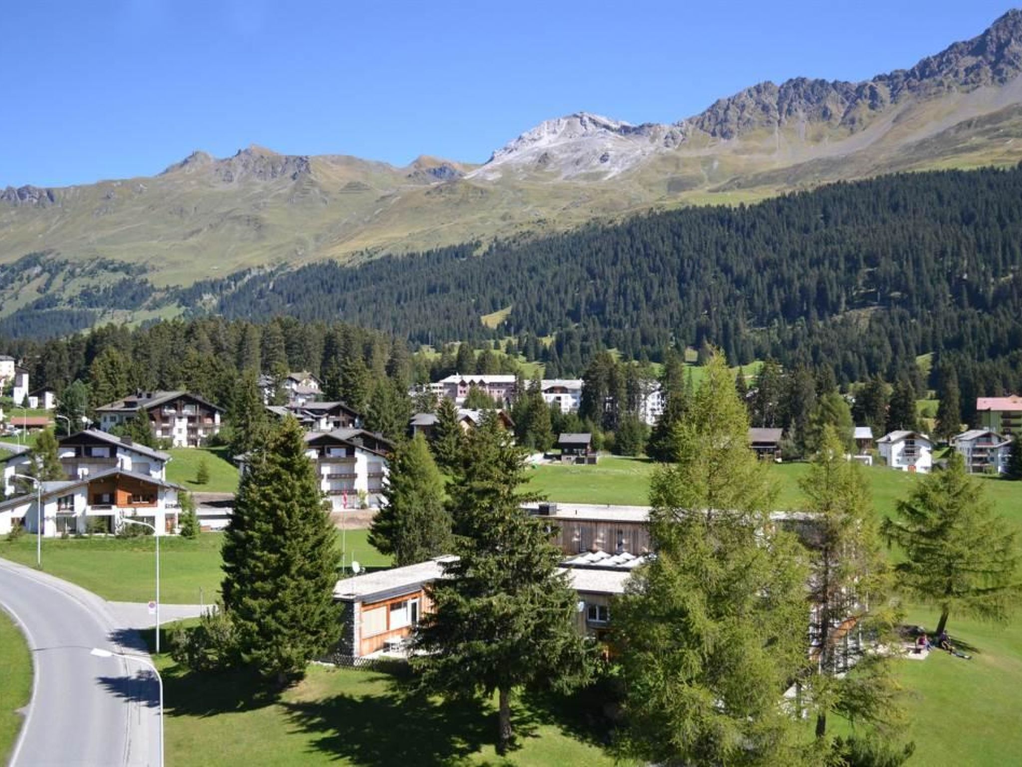 Un barrio residencial con casas rodeadas de árboles y montañas al fondo.