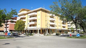 Ein mehrstöckiges Hotel mit Balkonen, einem überdachten Eingang und blauem Himmel.