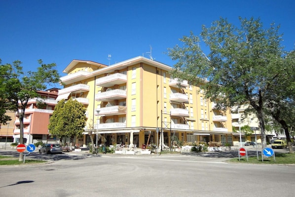 Ein mehrstöckiges Hotel mit Balkonen, einem überdachten Eingang und blauem Himmel.