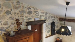 A room with a stone wall, wooden cabinet, table, chairs, and a hanging light fixture. - Gîte des Anges, 2 pers. swimming pool, direct access to the river La Méouge (Barret-sur-Méouge)