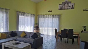A living room with a sofa, coffee table, dining area with chairs, and a table.