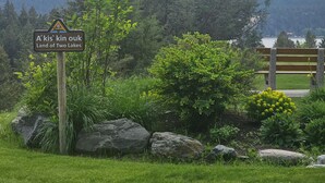 A sign reading "A'kis'kin ouk Land of Two Lakes" amidst a natural landscape with a bench and a view of mountains. - Lakeside 3 bed townhome w/ private beach access! (Windermere)
