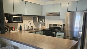 A modern kitchen with a large island, stainless steel appliances, and light blue cabinets. - Lakeside 3 bed townhome w/ private beach access! (Windermere)