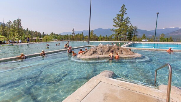 A swimming pool with clear water, surrounded by trees and mountains in the background. - Lakeside 3 bed townhome w/ private beach access! (Windermere)