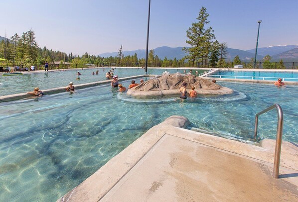 Relax by the serene pool surrounded by lush greenery and distant mountains.