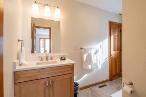 A bathroom with a wooden vanity, a mirror, a sink, and a towel rack.