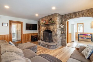 A living room with a stone fireplace, a television, and a billiards table. - Robyn`s Nest - Air Conditioning and Hot Tub! (Davis)