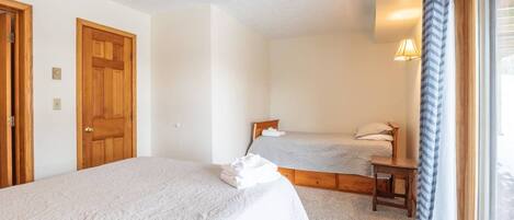 A bedroom with two single beds, wooden doors, and a window with curtains.