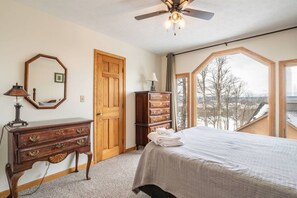 A bedroom with a bed, dresser, mirror, and a view of the outdoors.