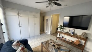 Ein Wohnzimmer mit einer Couch, einem Couchtisch, einem Fernseher und einem Deckenventilator.
