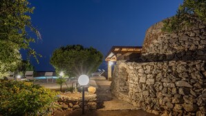 Eine Steinmauer, ein Weg und ein Gebäude mit Holzdach.