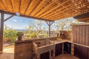 Una cocina exterior con encimera de piedra, armarios de madera y vistas al paisaje.