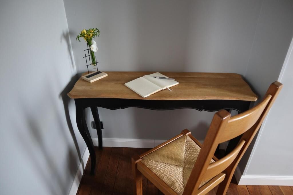 A wooden desk with a notebook and pen, a small plant, and a chair.