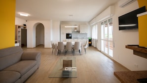 Un salon moderne avec une table basse en verre, un canapé et un coin repas comprenant des chaises et une table.
