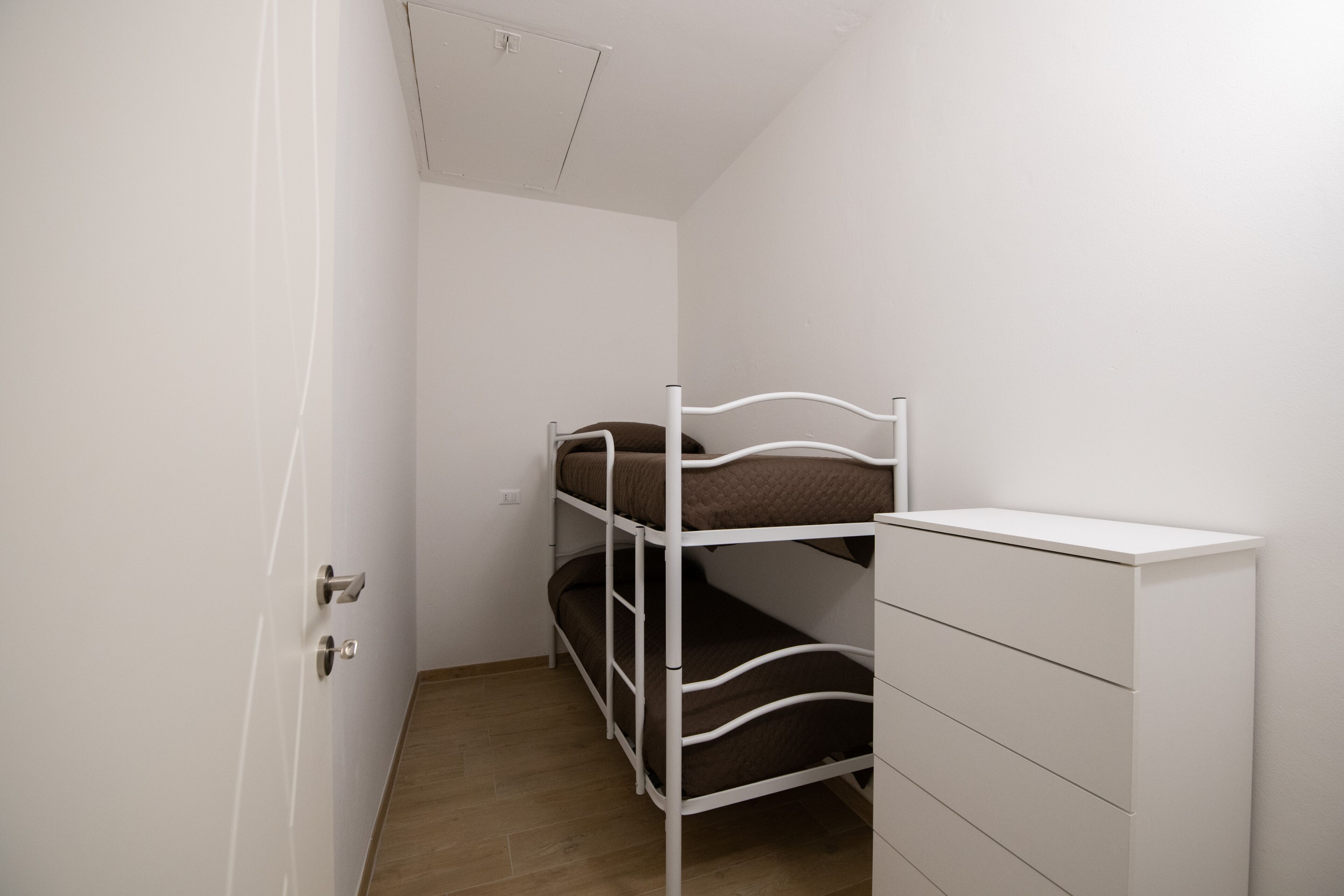 A small, compact room with a bunk bed and a white dresser.
