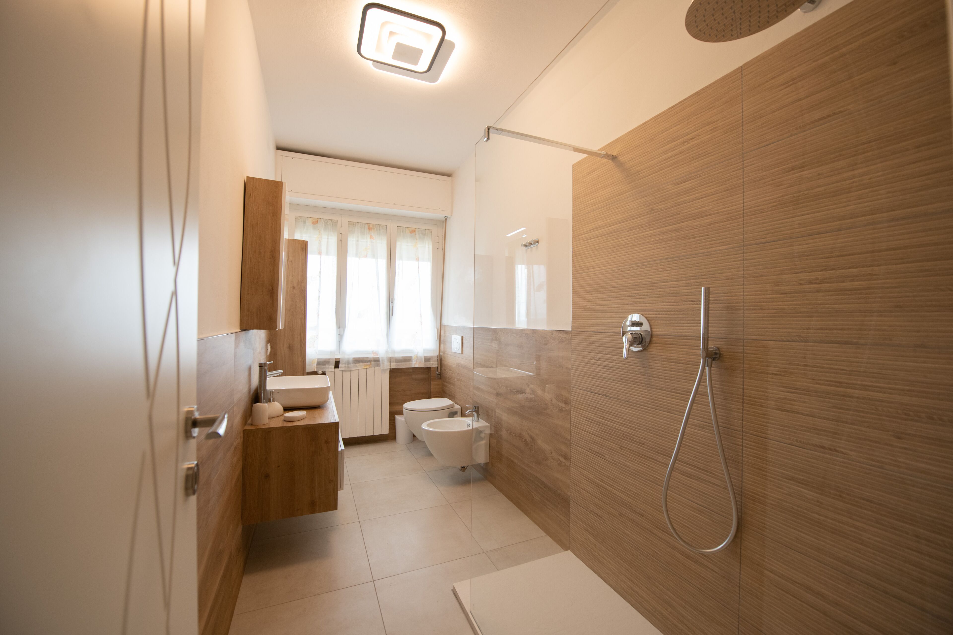 Une salle de bain moderne avec un meuble-lavabo en bois, des toilettes, un bidet et une douche.
