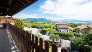 Un balcon donnant sur un quartier résidentiel, avec vue sur des maisons et des montagnes.