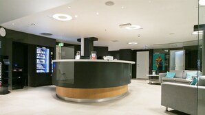 Een moderne receptie met een gebogen balie, een zithoek met een bank en een automaat.