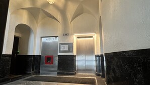 Een interieur met een marmeren vloer, een receptiebalie en een lift.