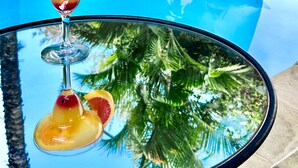 A poolside area with a lounge chair and a table with a drink. - Sous le Badamier Boutique Hotel & Spa (Grand-Baie)