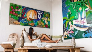 A woman reading on a sofa with a colorful mural behind her. - Sous le Badamier Boutique Hotel & Spa (Grand-Baie)