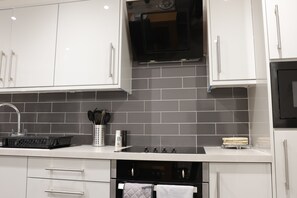 A modern kitchen with white cabinets, a black oven, and a tiled backsplash.
